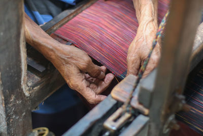 Cropped hands of senior person working at textile industry