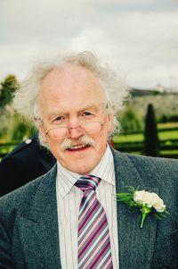 Portrait of senior man wearing boutonniere against sky