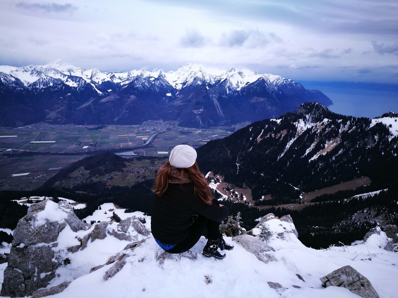 snow, cold temperature, winter, mountain, weather, nature, beauty in nature, real people, tranquil scene, mountain range, full length, scenics, snowcapped mountain, one person, tranquility, outdoors, warm clothing, rear view, day, leisure activity, lifestyles, adventure, sky, sitting, women, people