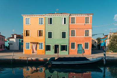 Buildings by canal against sky in city