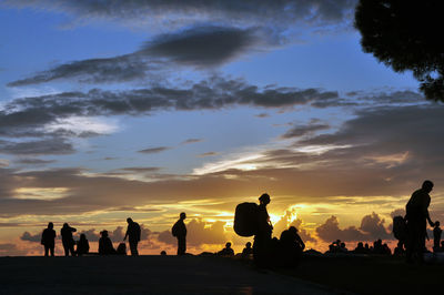 Silhouette people at beach against sky during sunset