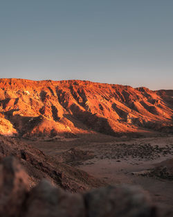 Scenic view of land against clear sky during sunset