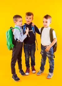 Portrait of boy standing against yellow background