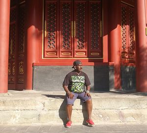 Full length of man sitting outside building