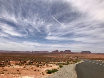 Road amidst field against sky