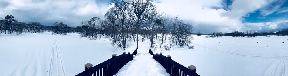 Panoramic view of snow covered field against sky