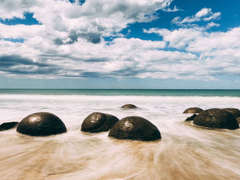 Rocks on beach against sky