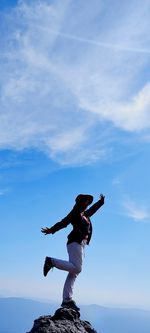 Rear view of man jumping against sky