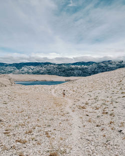 One person, tiny human in big world. walking on path on rocky terrain.