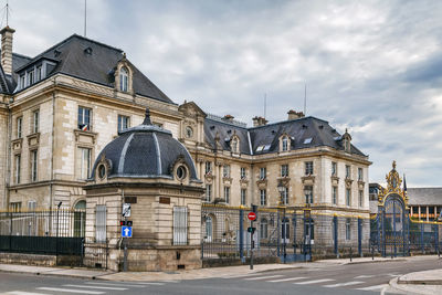 Road by buildings against sky in city