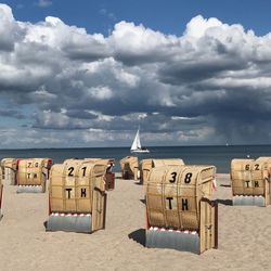 Hooded chairs on beach against sky