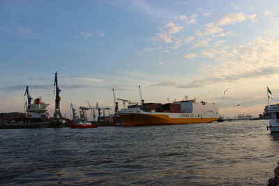 Silhouette of cranes in sea against sky