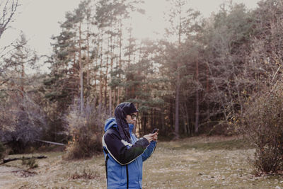 Side view of man photographing camera in forest