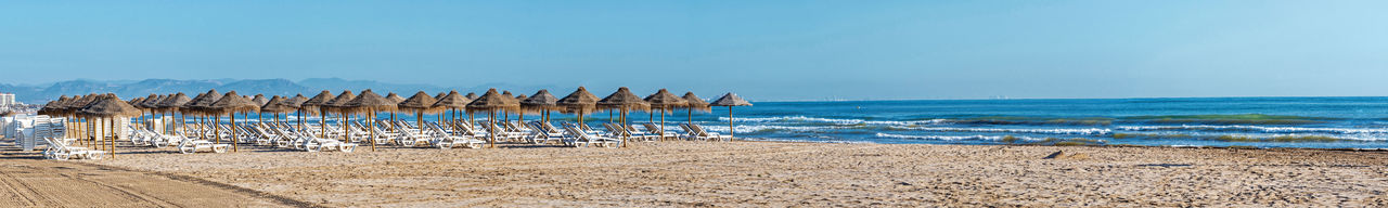 Wooden posts on beach against clear blue sky