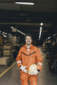 Portrait of smiling male worker in protective workwear standing in warehouse