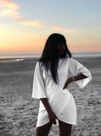 Beautiful woman standing at beach during sunset