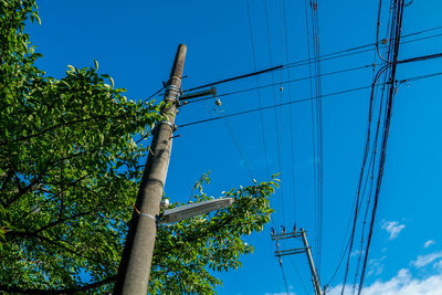 Low angle view of electricity pylon against blue sky