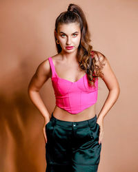 Portrait of young woman standing against wall