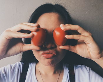 Close-up of woman covering eyes with tomatoes