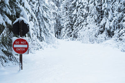 Road sign against frozen trees on snow covered field