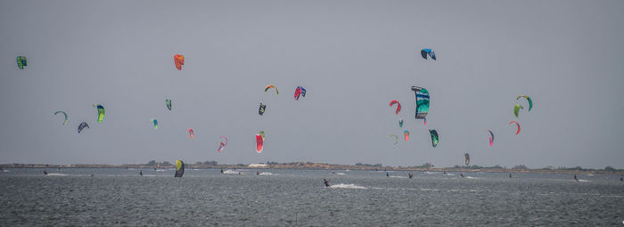 People flying over beach against sky