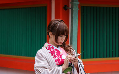 Full length of woman standing against red wall