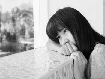 Close-up of woman leaning on window