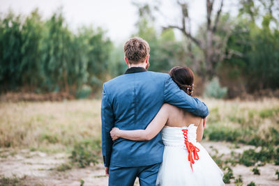 Rear view of couple kissing against trees