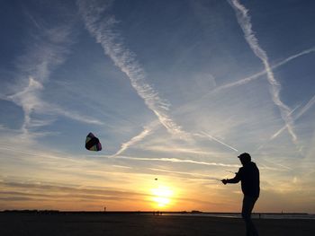 Silhouette man flying kite at beach