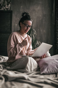 Full length of woman sitting on bed