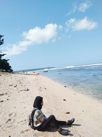 Rear view of woman sitting on beach