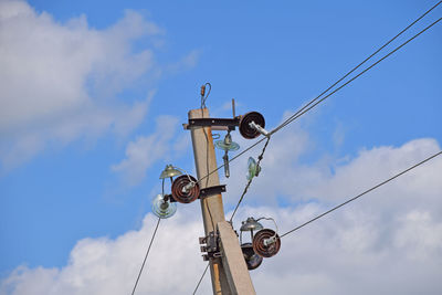 Low angle view of electricity pole against cloudy sky