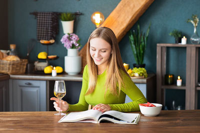 Young woman reading book while sitting at home