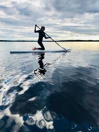 Silhouette man surfing in sea against sky