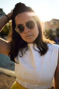 Portrait of young woman with hand in hair standing outdoors