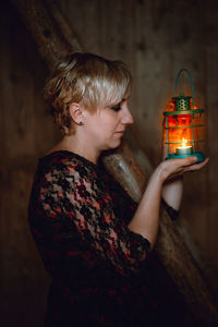 Side view of woman holding illuminated candle