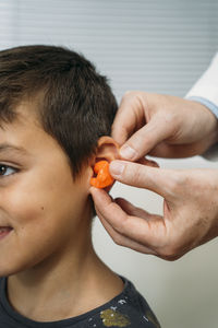 Male audiologist putting hearing air in child's ear at clinic