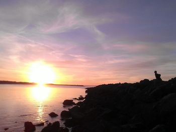 Silhouette of people on rocks at sunset