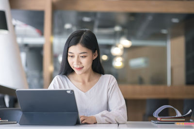 Businesswoman using digital tablet at desk in office