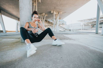 Full length of woman sitting on street