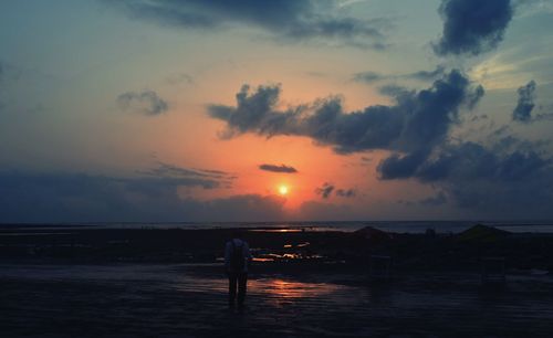 Silhouette woman standing on beach against sky during sunset