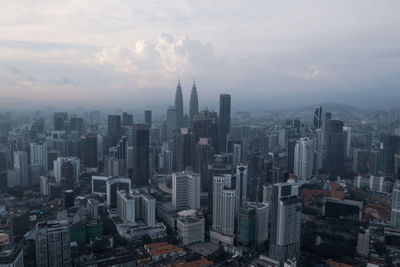 Aerial view of buildings in city against sky