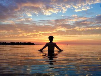 Silhouette of a tourist in swimming pool at sunset