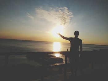 Silhouette man standing by sea against sky during sunset