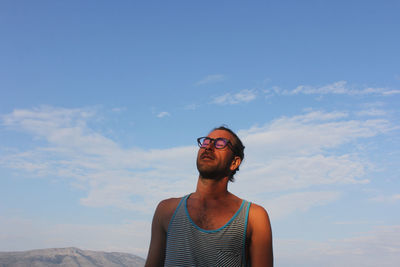 Low angle view of young man standing against sky