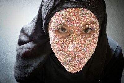 Close-up portrait of woman in hijab with colorful sprinkles on face