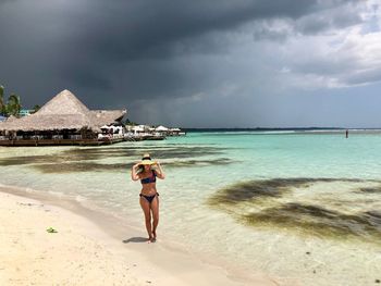 Full length of woman walking at beach against sky