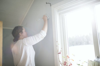 Woman painting wall at home