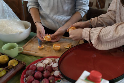 Midsection of women peeling of orange fruits