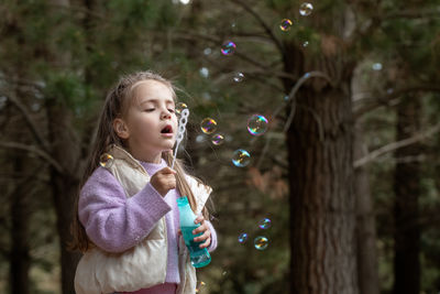 Young woman blowing bubbles in forest